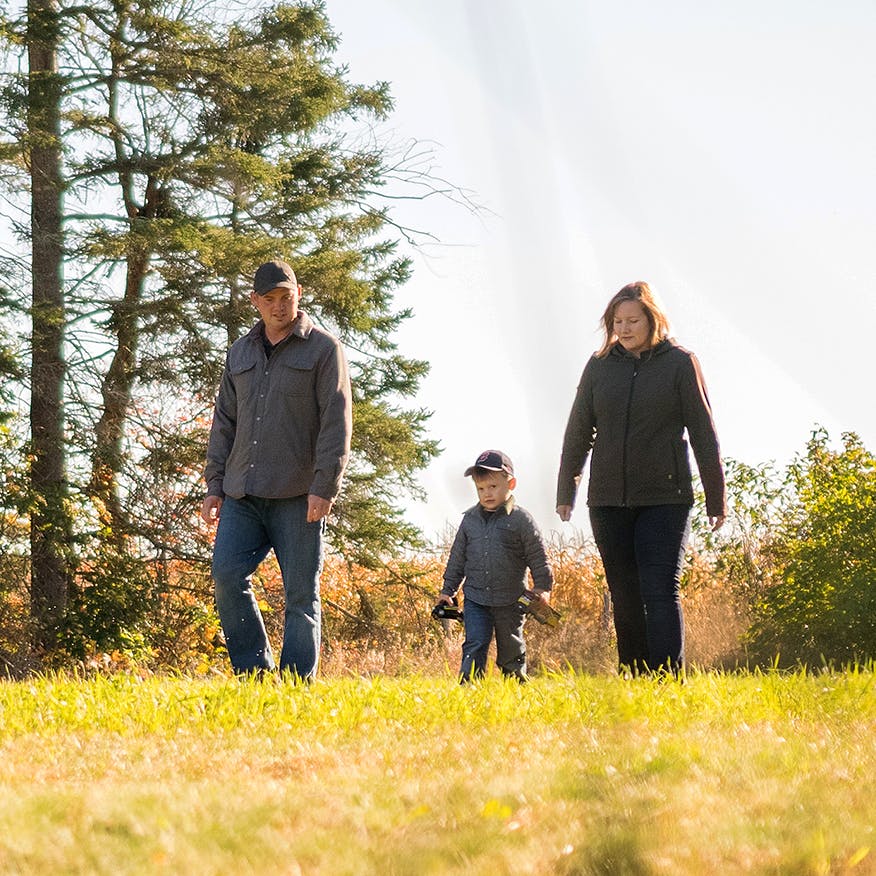 man and woman play with their child outdoors