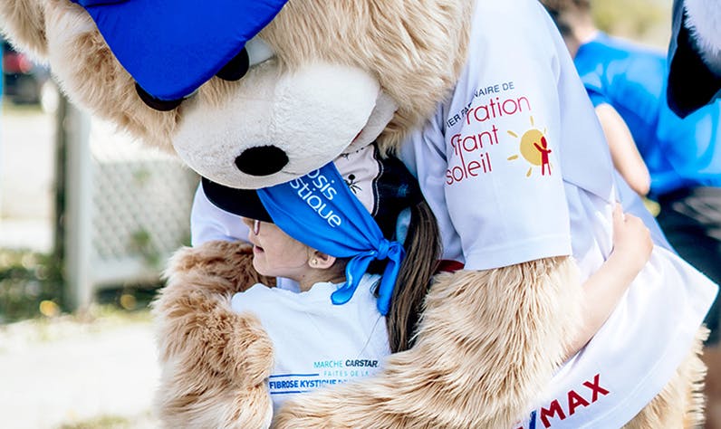 mascotte étreignant un jeune enfant lors d'une activité-bénéfice