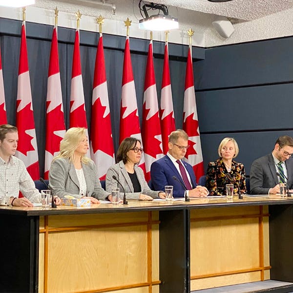 conférenciers assis à une table devant des drapeaux canadiens