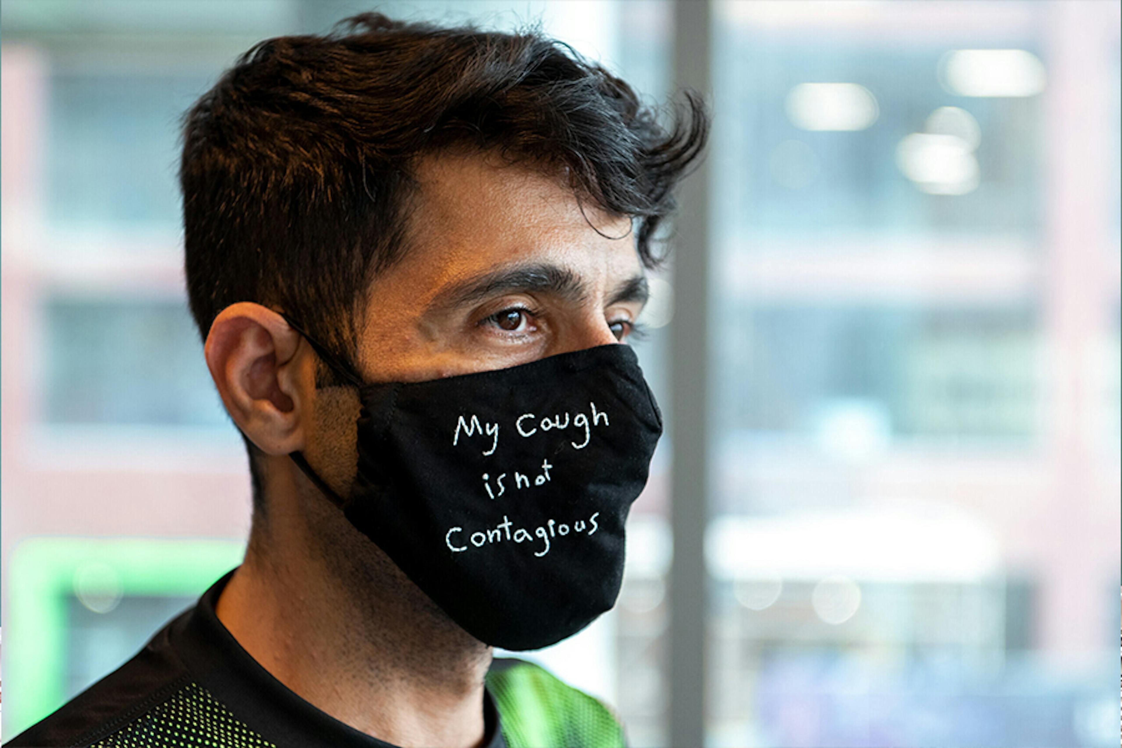 Man poses with mask that reads ‘my cough if not contagious’