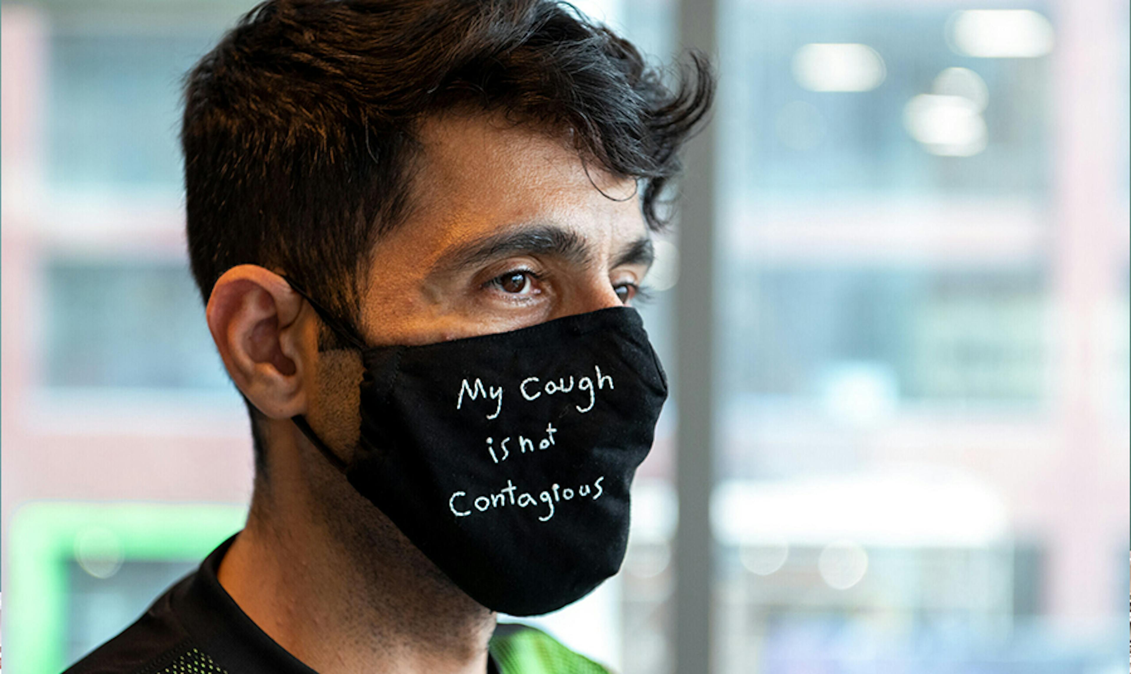 Man poses with mask that reads ‘my cough if not contagious’