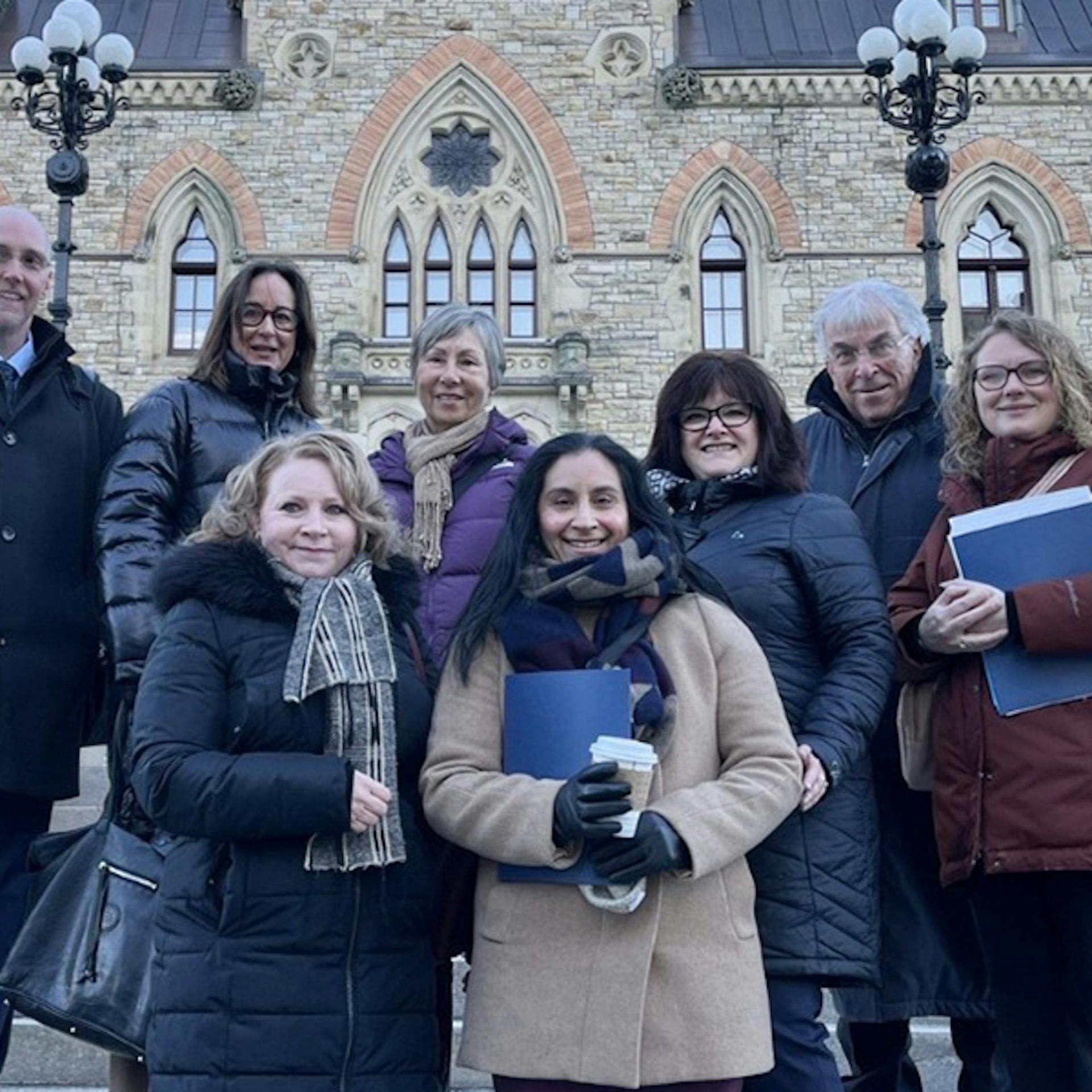 A group of people pose together outside Ottawa’s Parliament Buildings