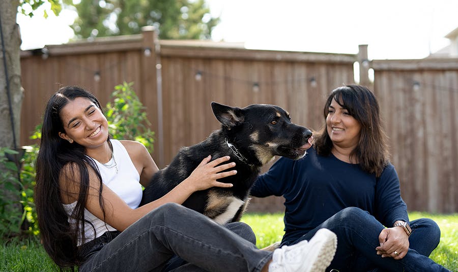 Two women and their dog play in a backyard