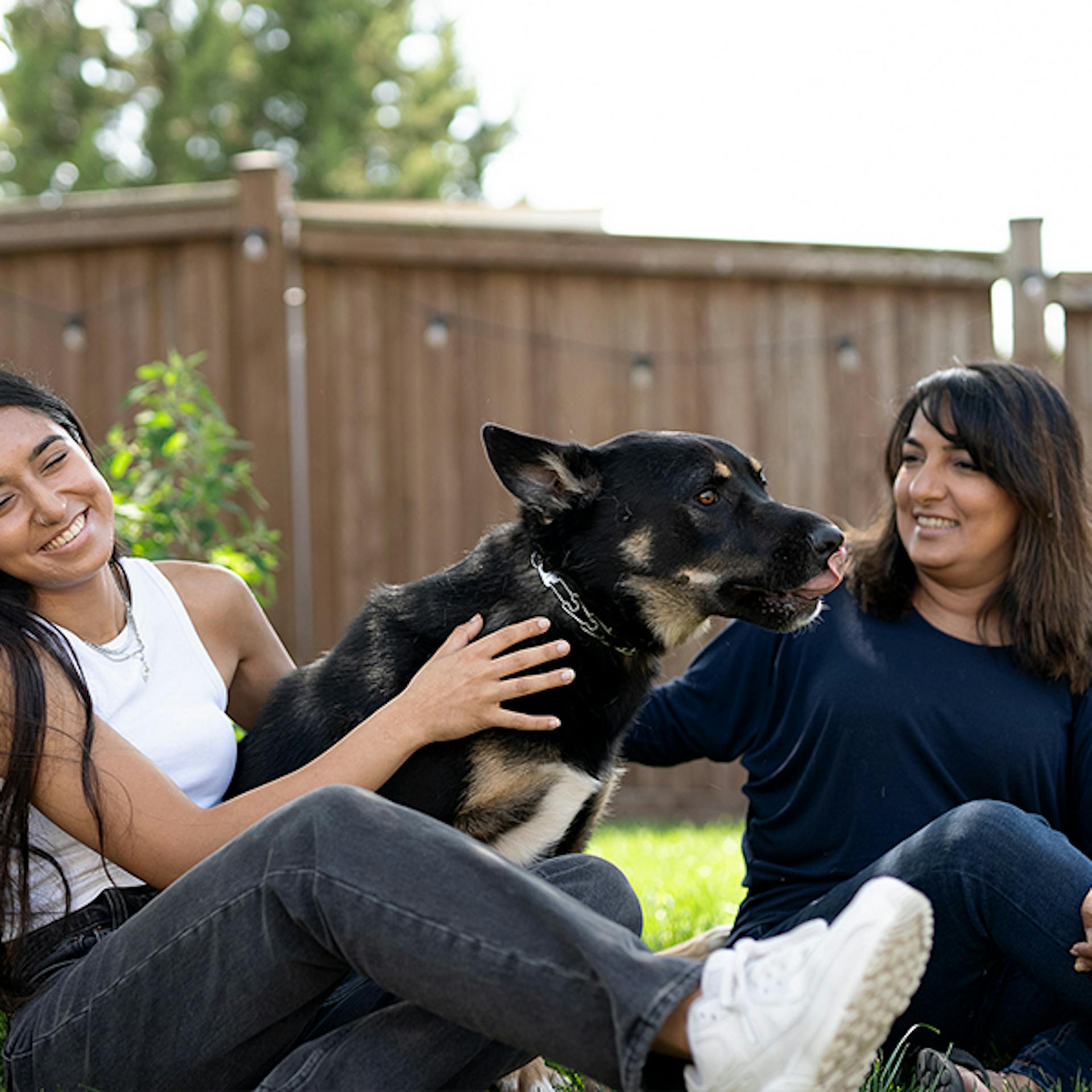 Two women and their dog play in a backyard