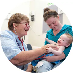 A doctor checks the heart rate of an infant in her mother's arms