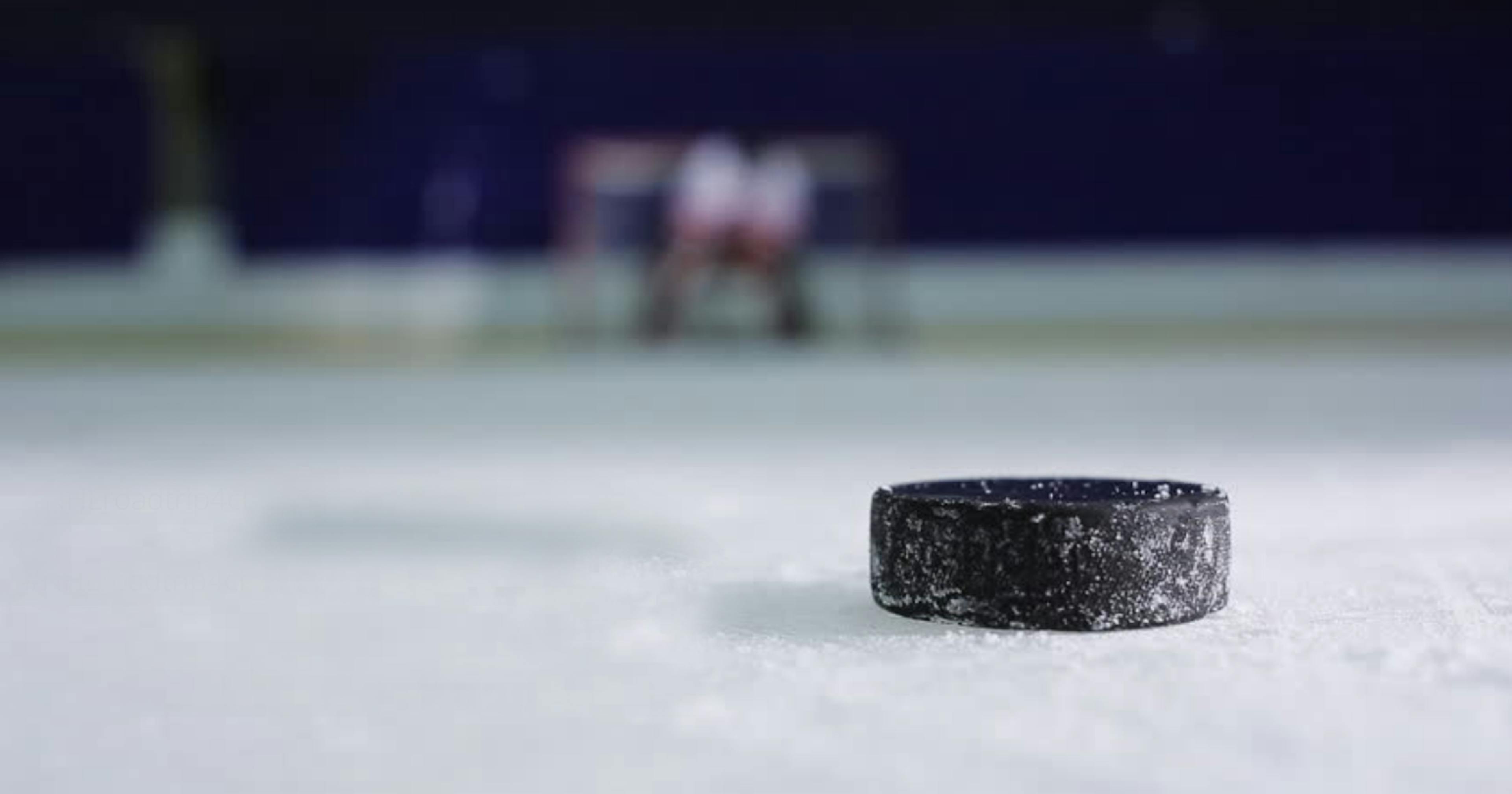 Un gros plan d’une rondelle de hockey sur une patinoire intérieure.