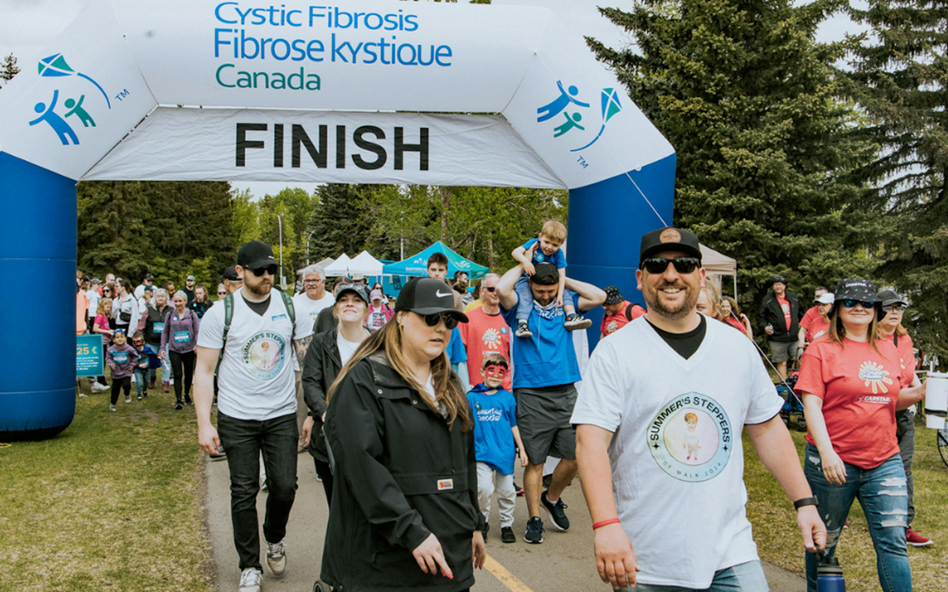 A large group of walkers cross the finish line banner