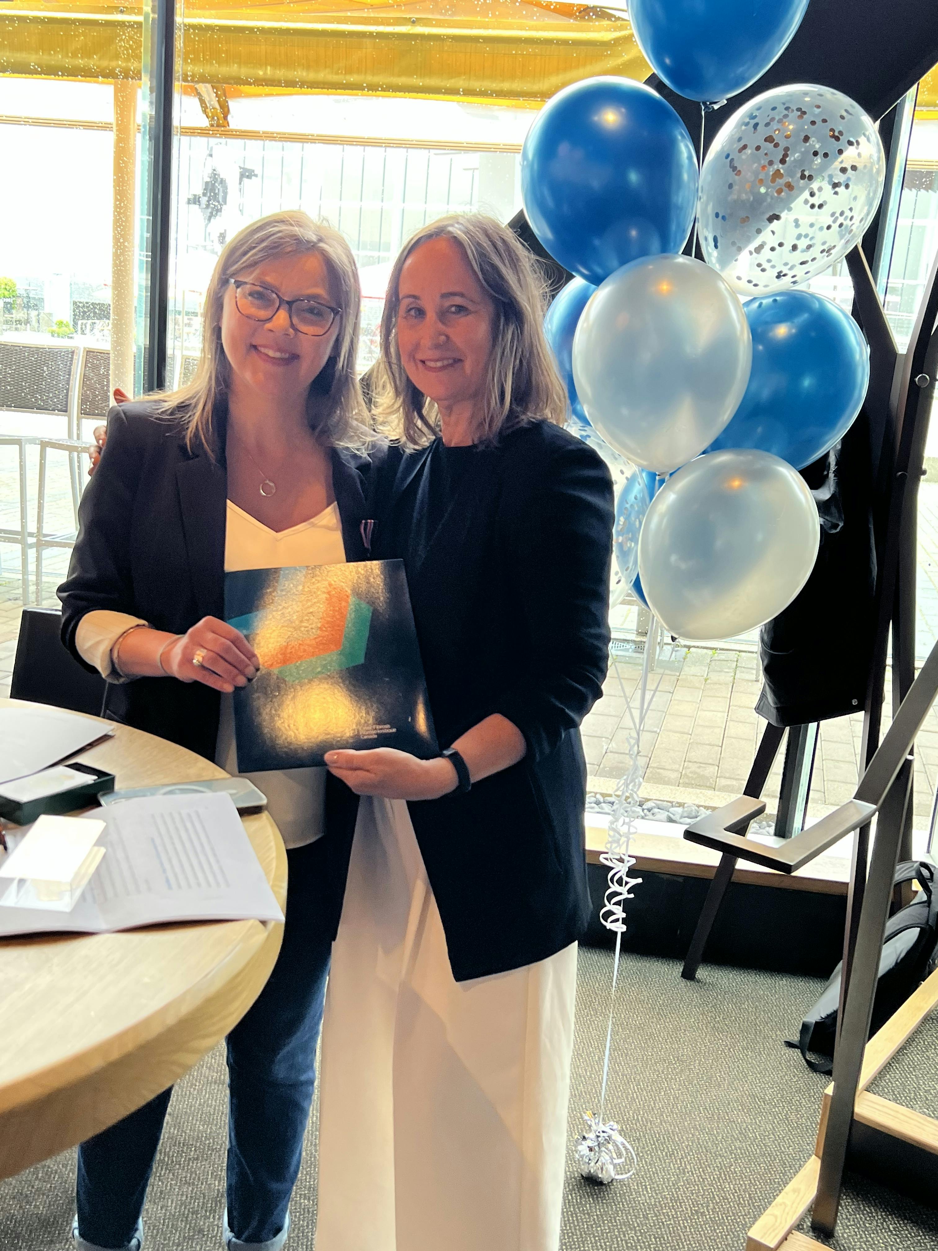 Kim Wood stands with Kelly Grover and accepts the KCCM