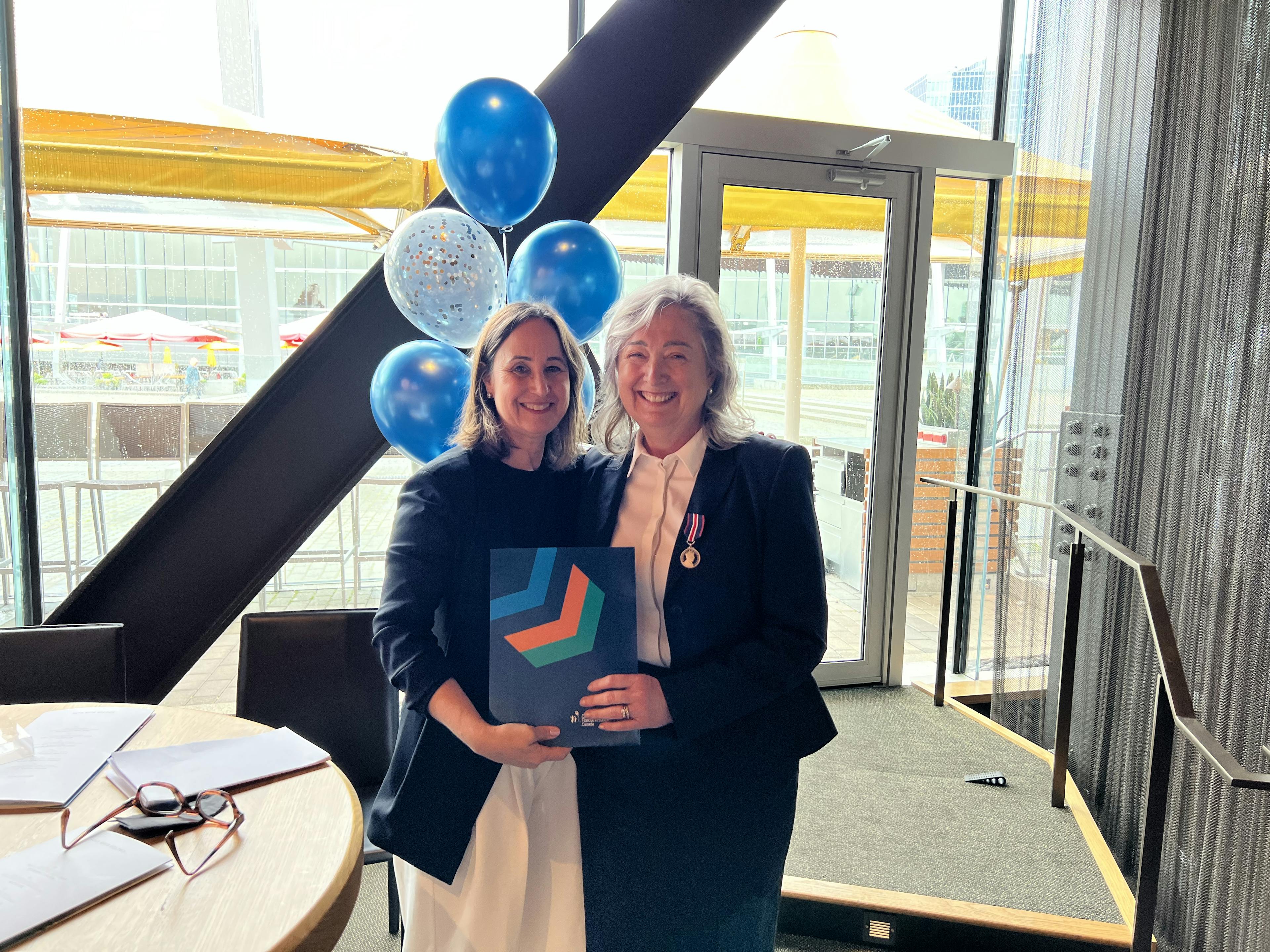 Kelly Grover stands with Leona Pinsky as she accepts her KCCM