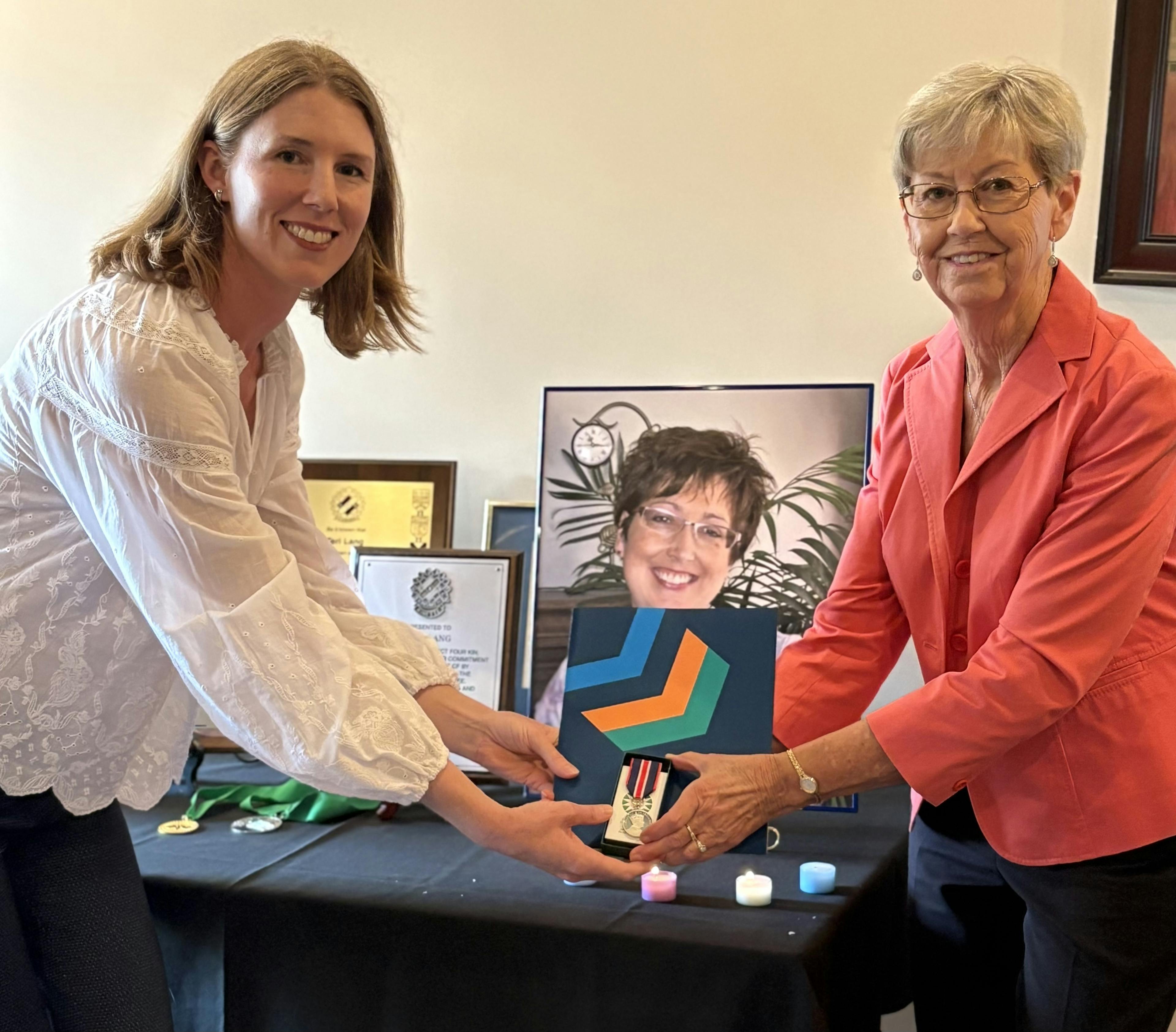 Jacqui Greenhorn accepts the King Charles III Coronation Medal from Aisha Champness on behalf of Teri Lang.