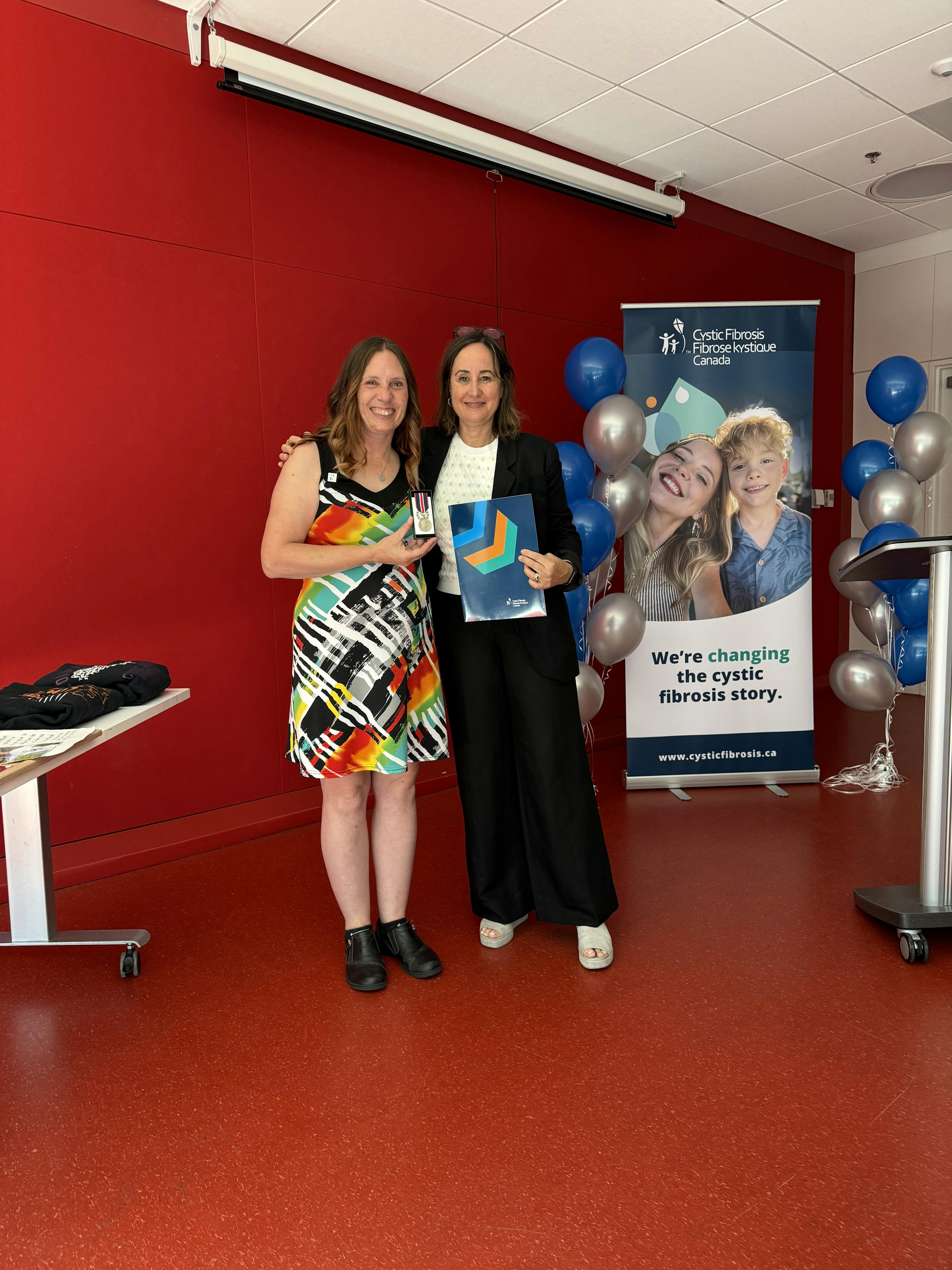 Agatha Bourassa accepts the King Charles III Coronation Medal from Kelly Grover