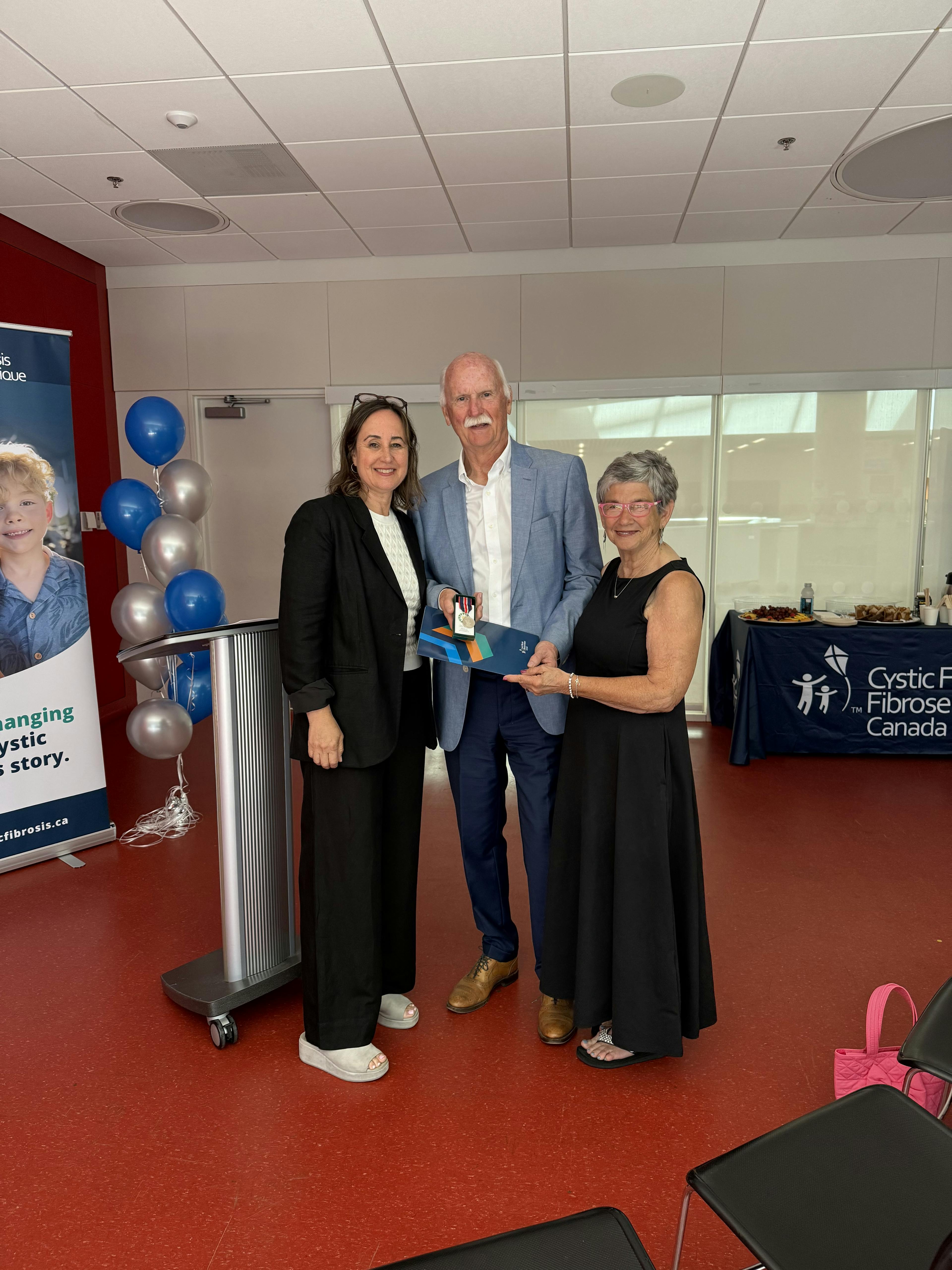 Ian Thompson accepts the King Charles III Coronation Medal from Kelly Grover