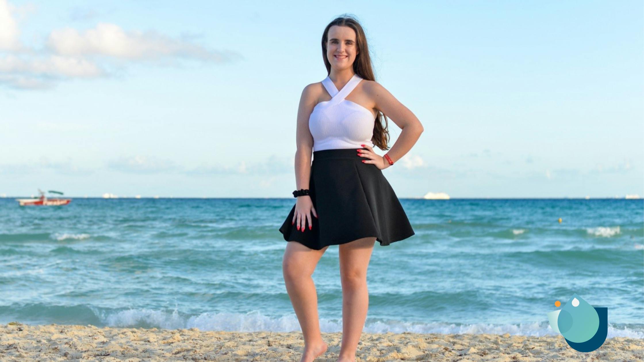 Lauren standing on a beach in front of the blue water