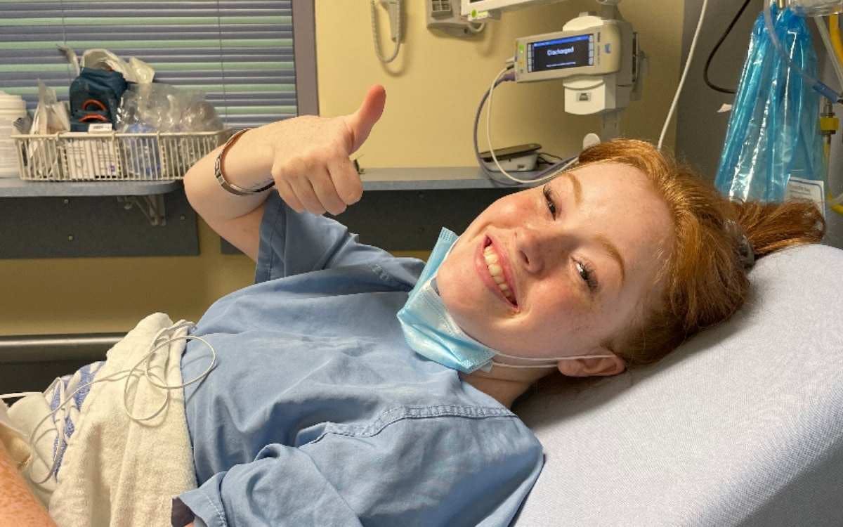 Une femme souriante allongée sur un lit d'hôpital.