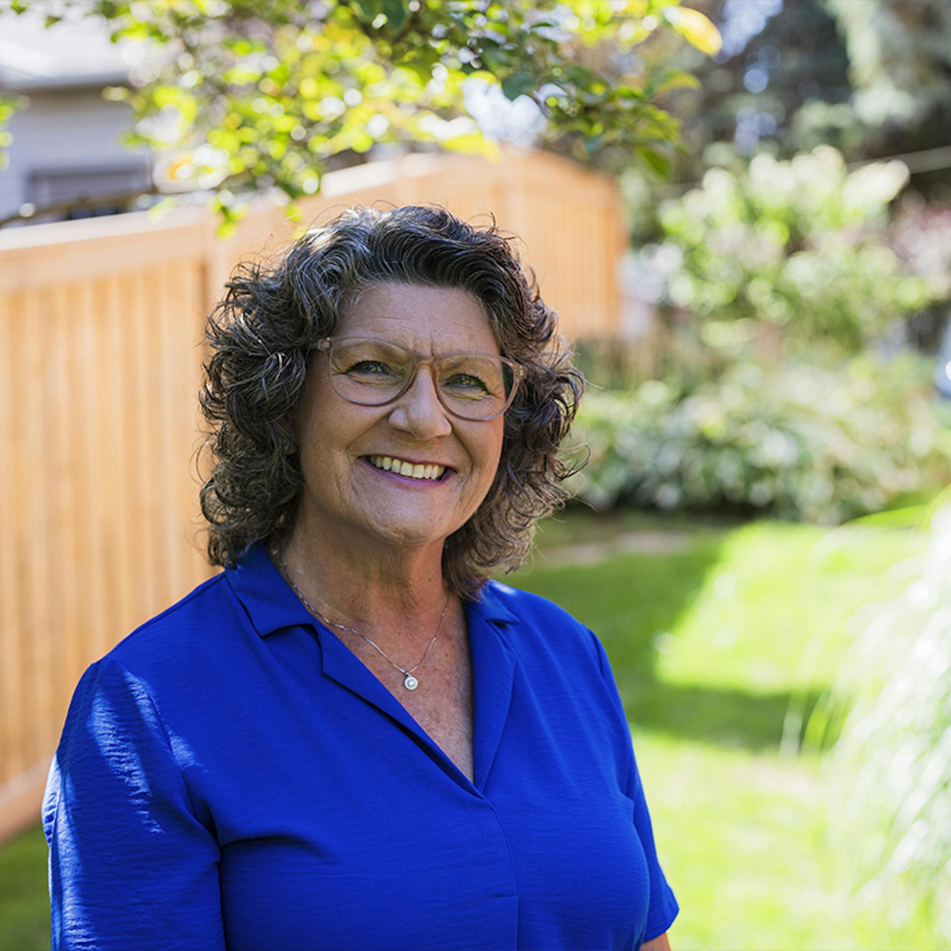 Former CF nurse, Louise, smiles outside in her yard.  