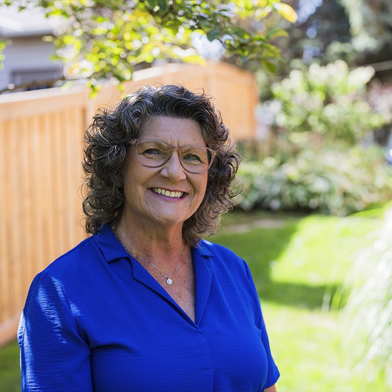Former CF nurse, Louise, smiles outside in her yard.