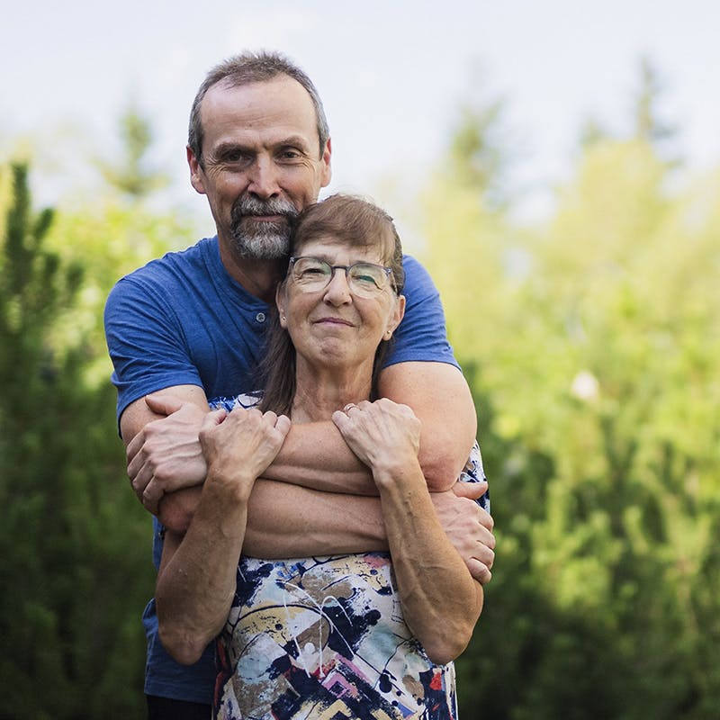 An older woman with CF embraces her husband.
