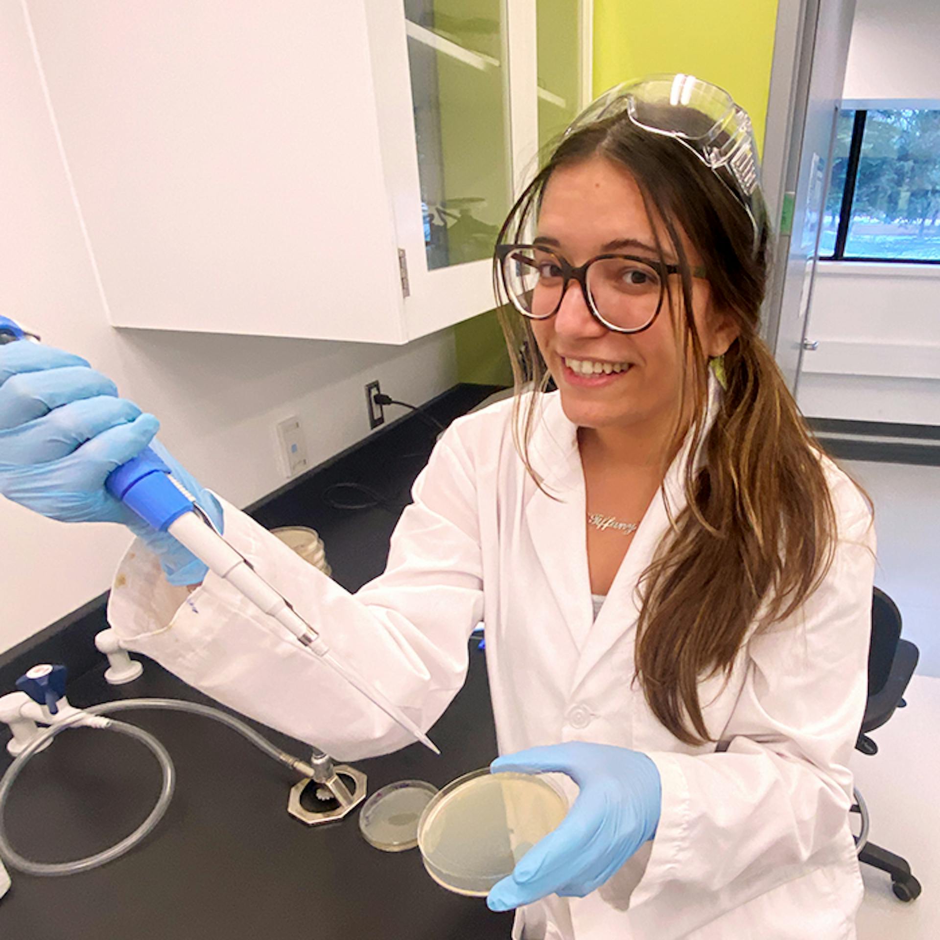 Une jeune femme portant une blouse de laboratoire et des gants dans un laboratoire scientifique.