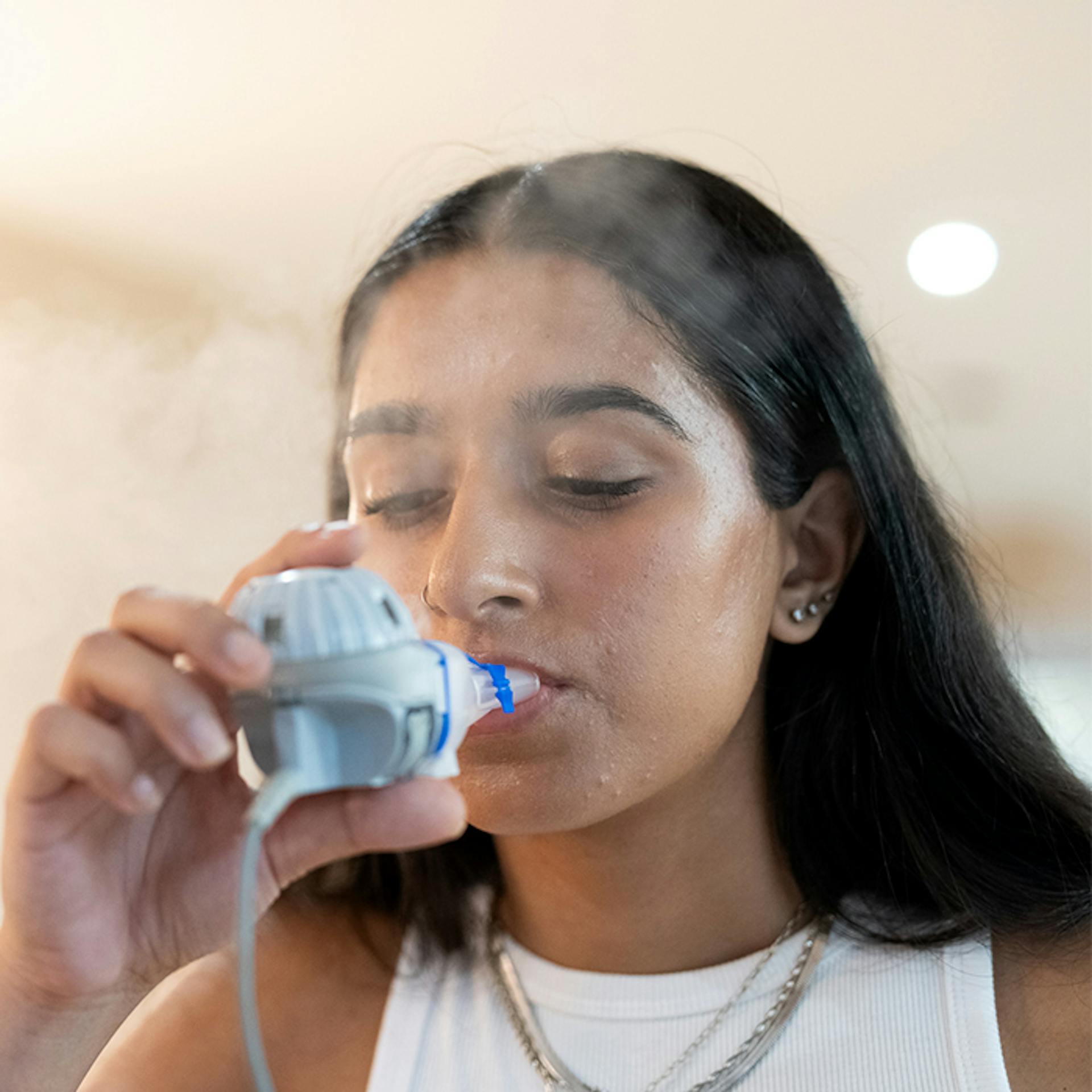 Une jeune femme utilisant un nébuliseur pour le traitement de la fibrose kystique.