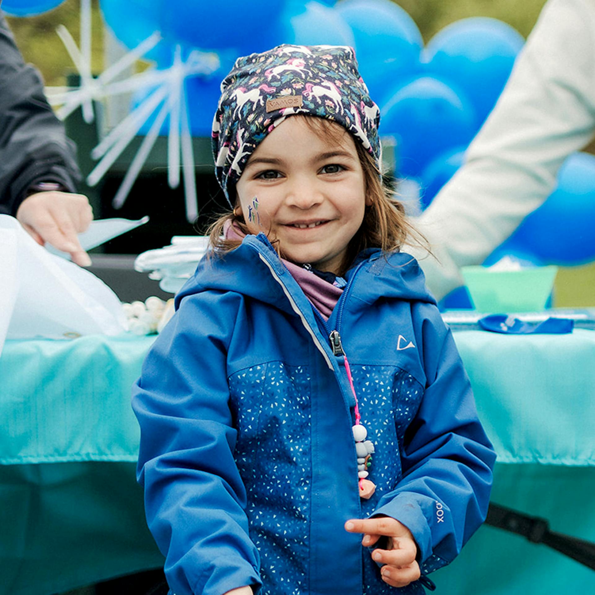 Un jeune marcheur portant un bandana et un imperméable bleu.