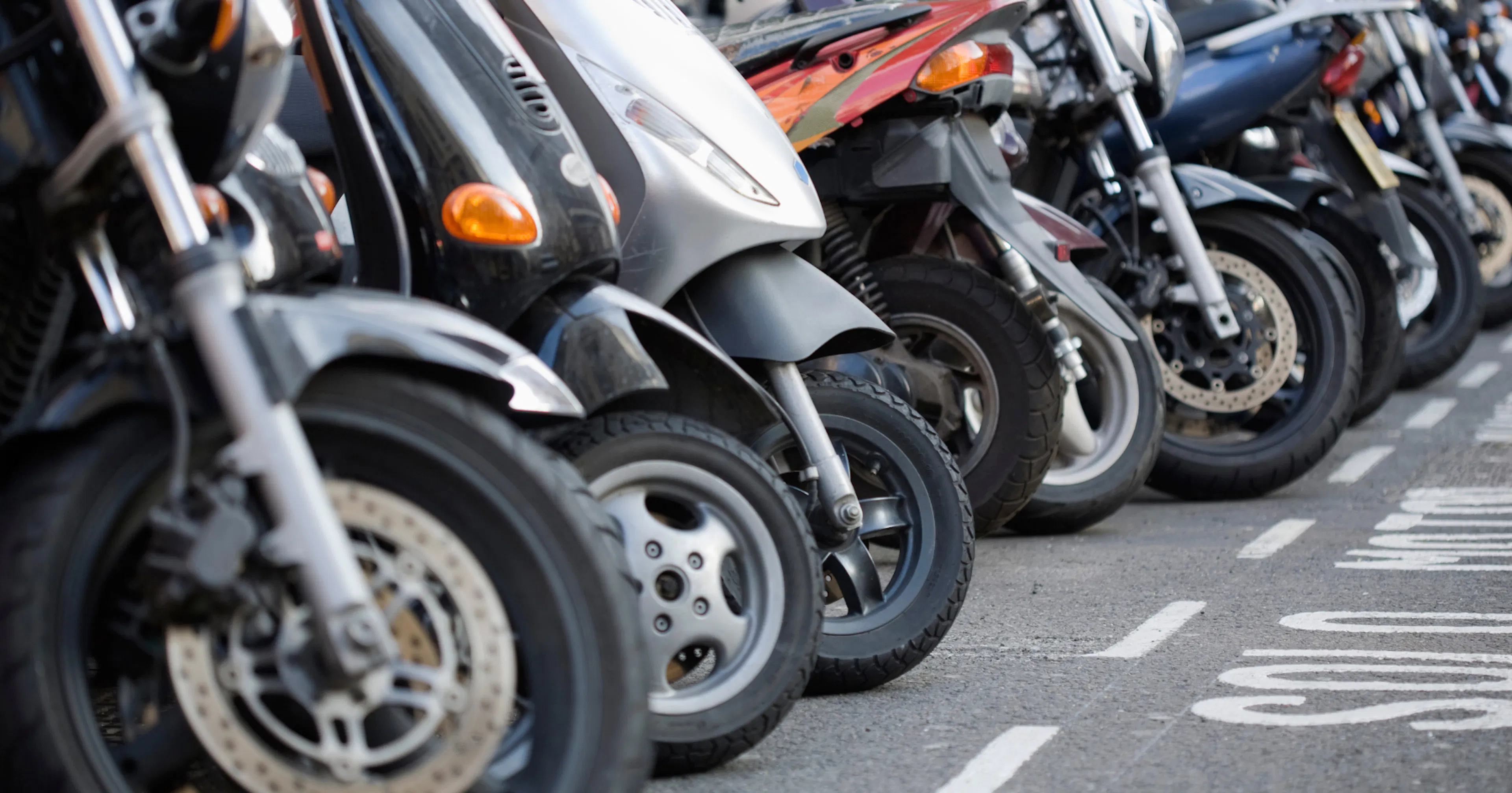 A large group of motorbikes are parked on the street.