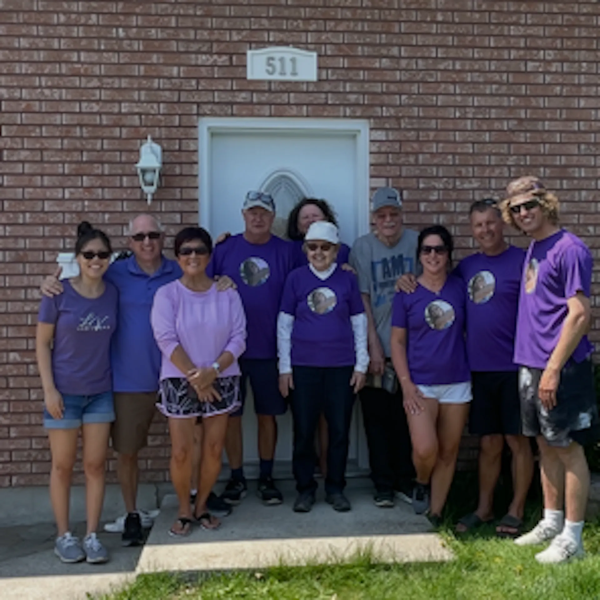A group of people wearing purple t-shirts with a young woman's face on them.