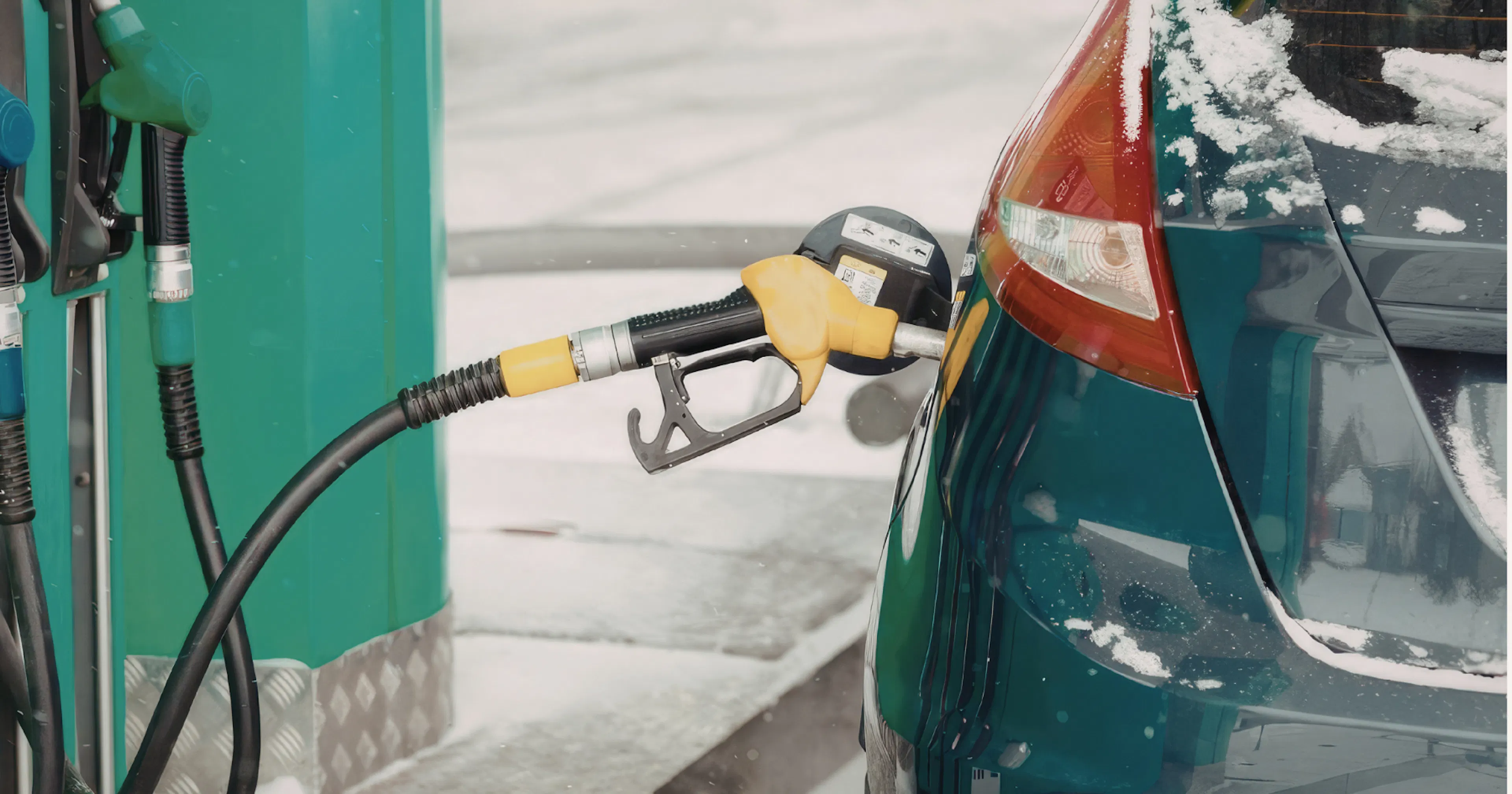 Car parked in a gas station with a gas pump being in use.