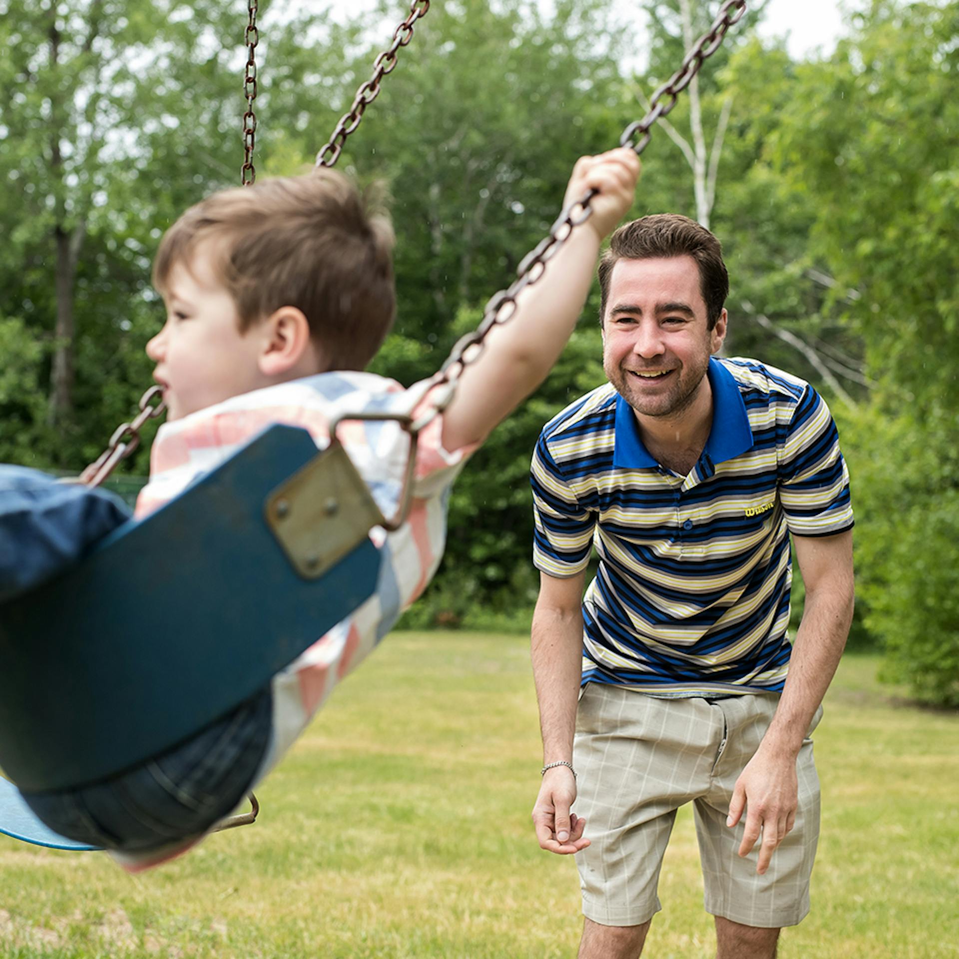 A man pushes a toddler on a swing