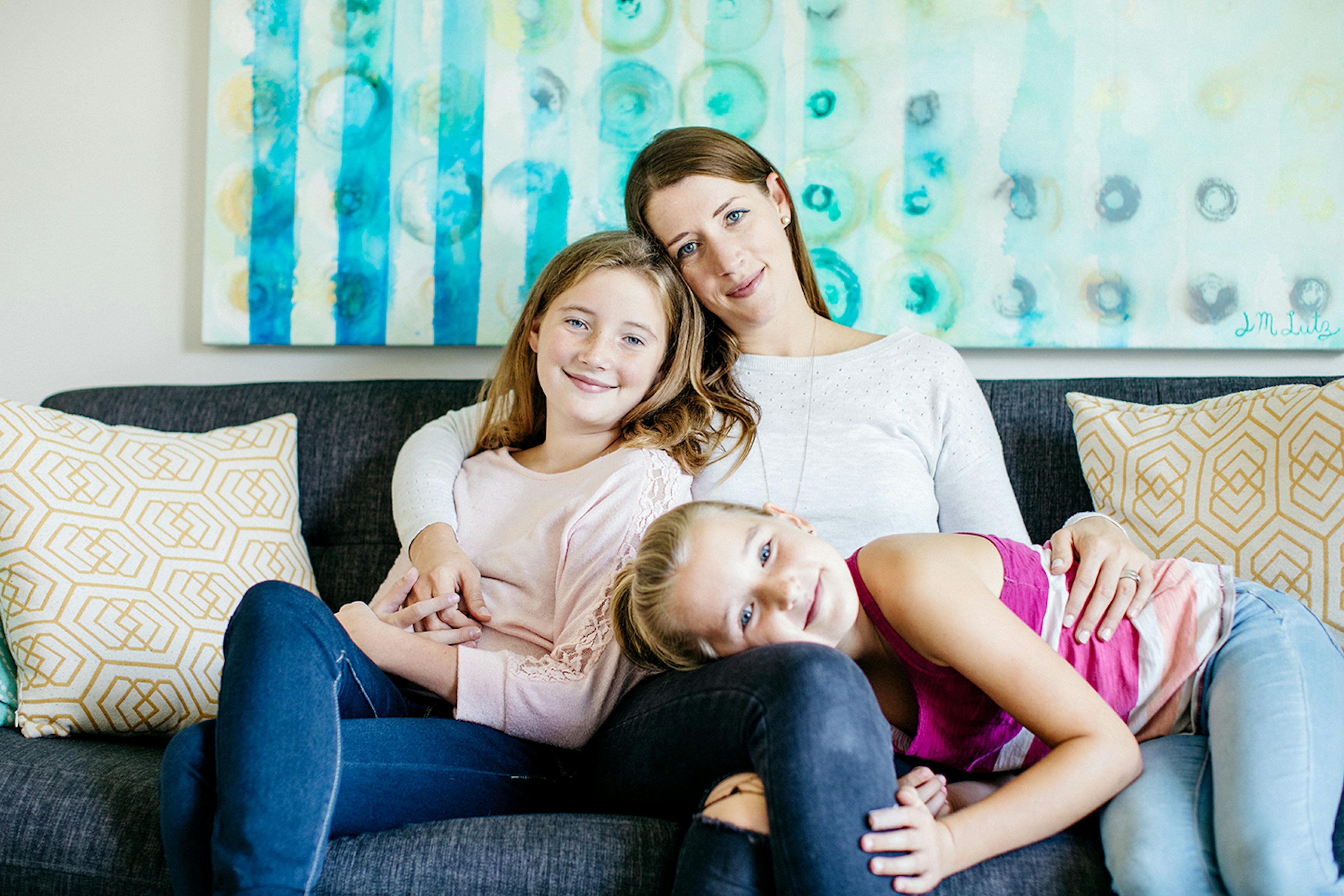 A relaxed mother and her two daughters sit together.