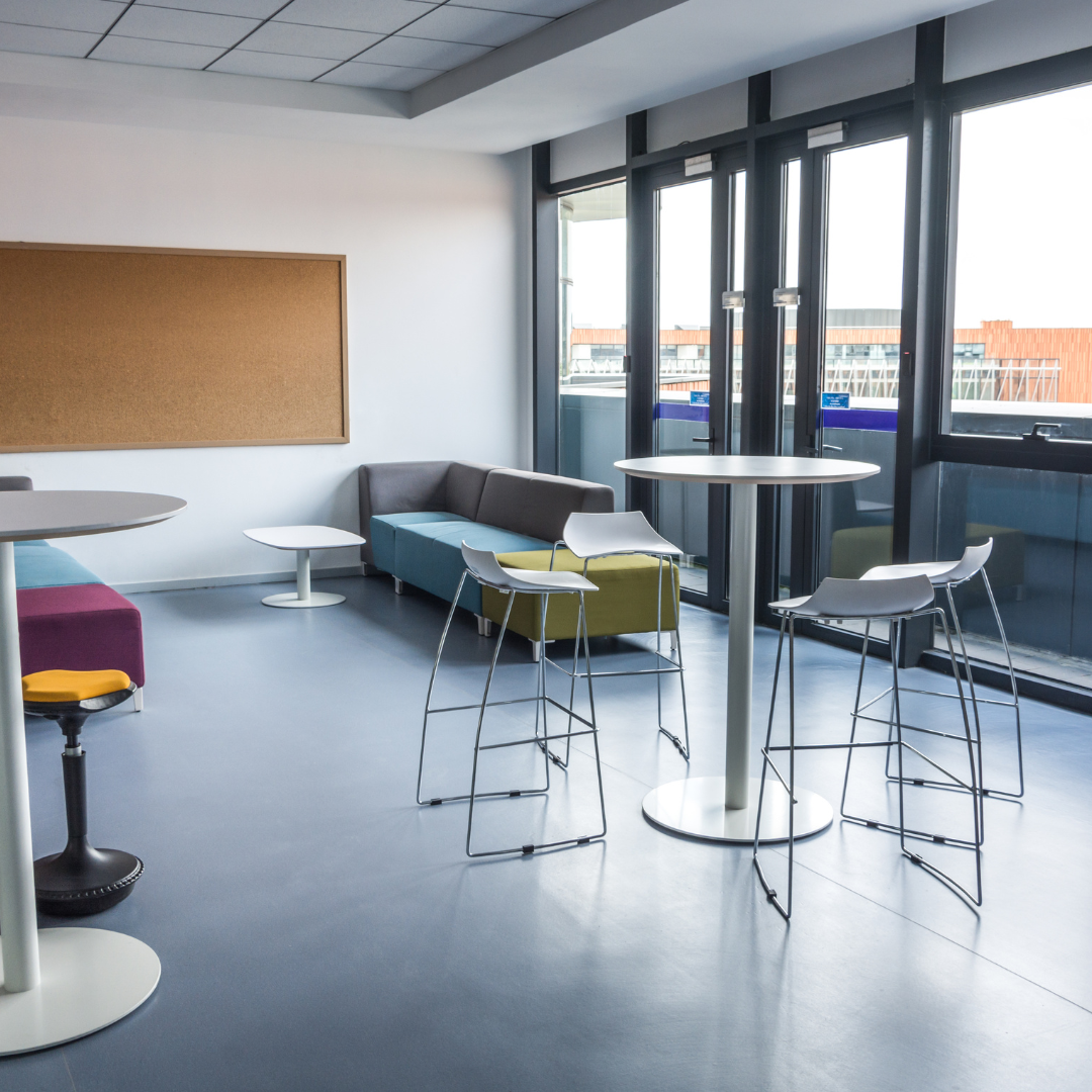 Espace d'accueil pour le public avec des tables hautes, des chaises et des canapés