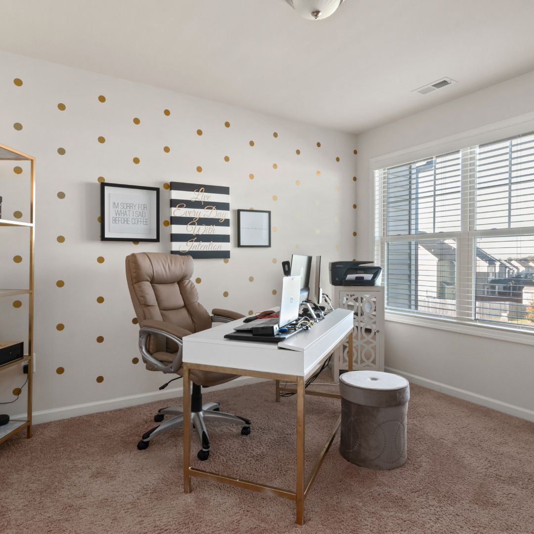Un salon avec un bureau avec une tapisserie personnalisée, une chaise et un tabouret