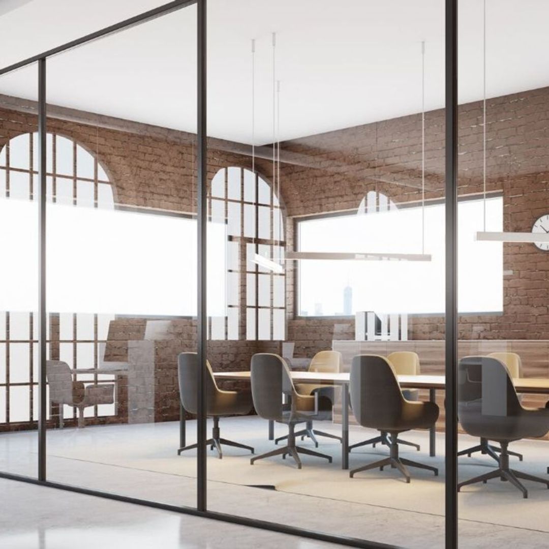 Une grande verrière avec un bureau, une grande table et des chaises