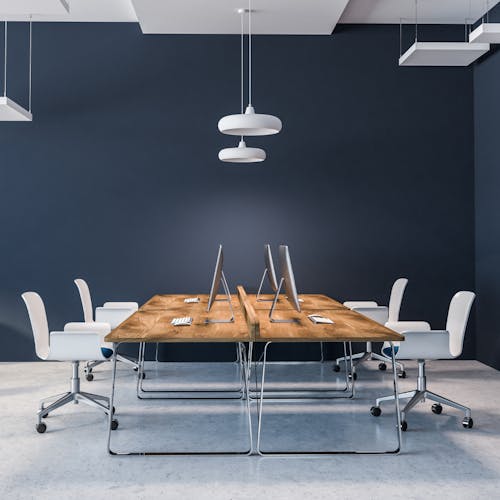 Espace de travail avec les murs bleu et  une grande table avec 4 postes de travail