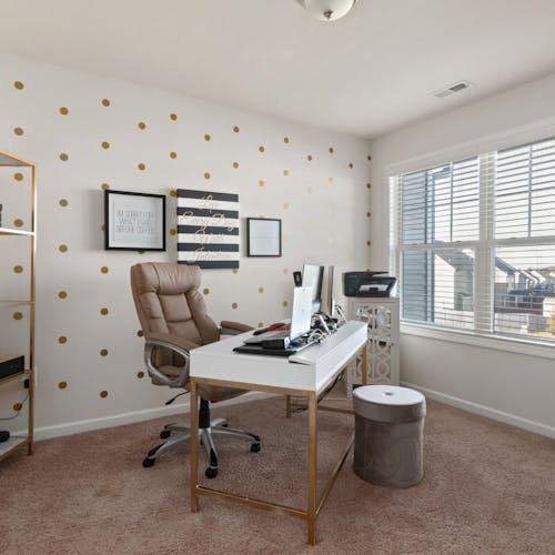 Un salon avec un bureau avec une tapisserie personnalisée, une chaise et un tabouret