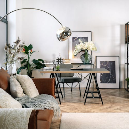 Un bureau dans le salon avec une chaise, une table une grande lampe, des plantes et un ordinateur