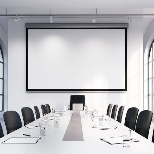 Salle de réunion avec un tableau blanc, une table blanche et des chaises
