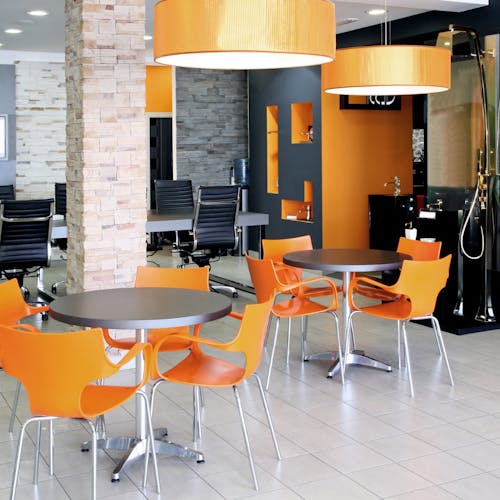 Espace de travail avec des bureau, des chaises orange et un sol avec du carrelage