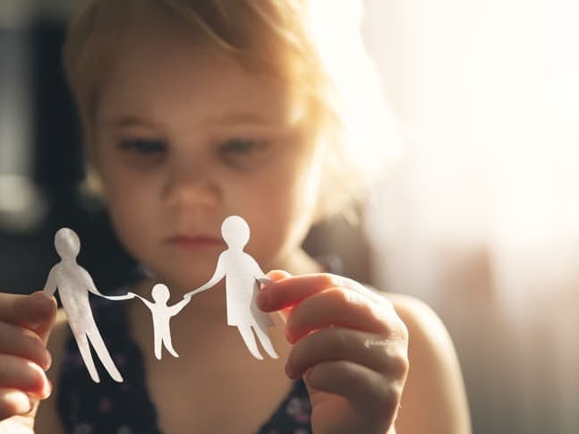 skyrybos-ir-vaiku-dalybos-mergaite-rankoje-laiko-seimos-popierines-iskarpas