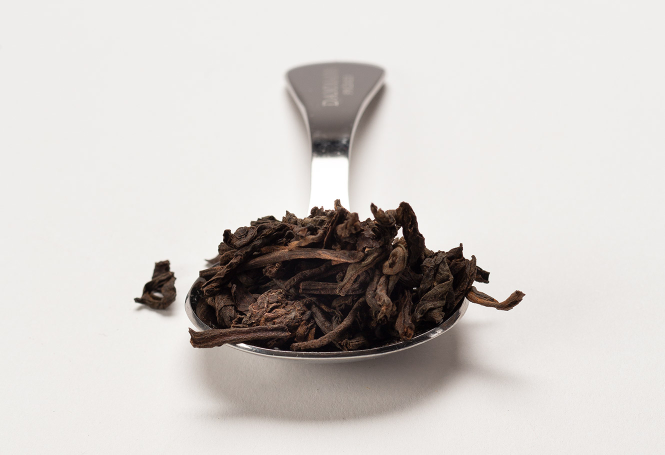 Cuillère à mesurer en acier inoxydable avec du thé sombre en vrac.