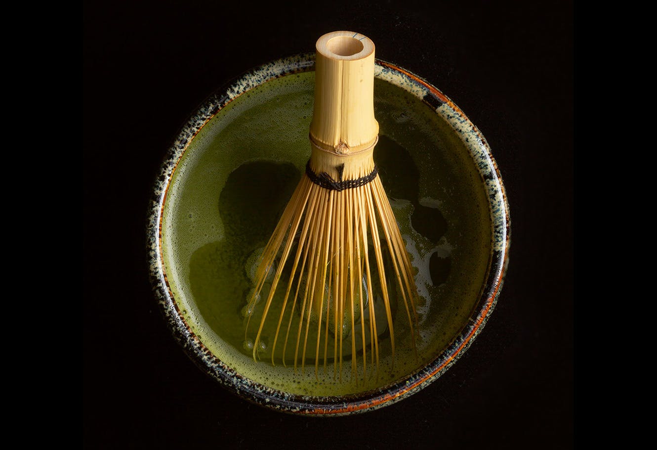 Matcha green tea liqueur bowl with bamboo chasen whisk.