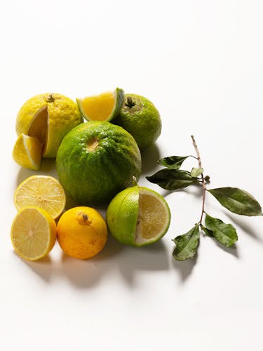 Whole and cut fruits of yellow and green bergamots.