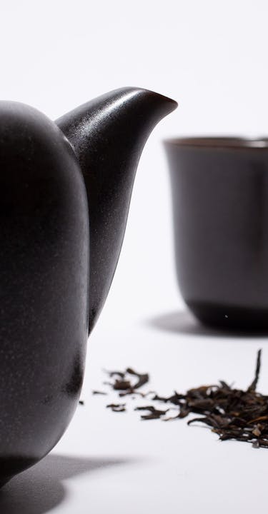 Japanese smoked tea leaves in bulk with a black cup and a black teapot.