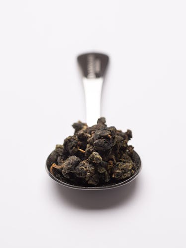 Cucchiaio dosatore in acciaio inox con tè oolong sfuso.