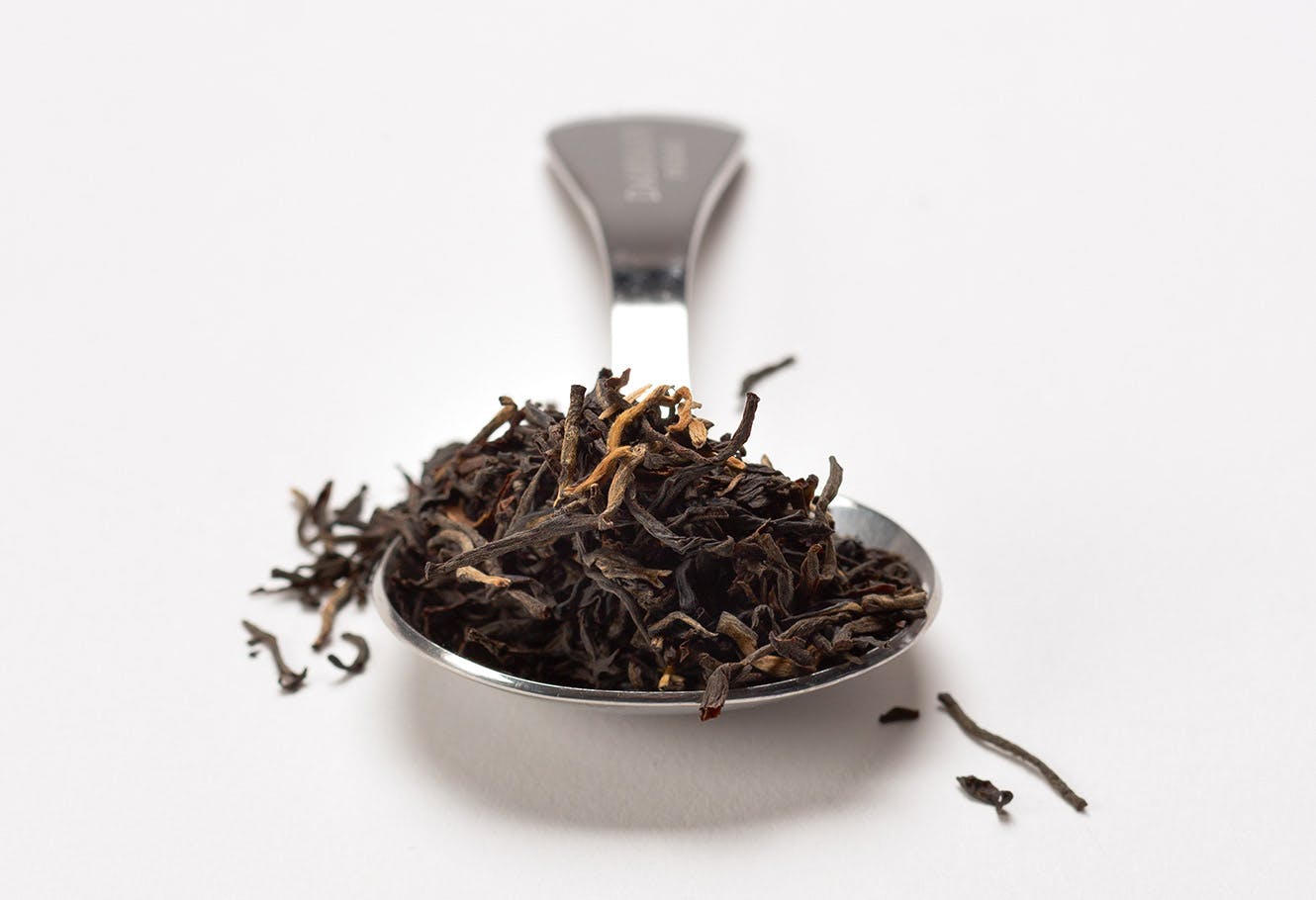Cuillère à mesurer en acier inoxydable avec thé noir en vrac.