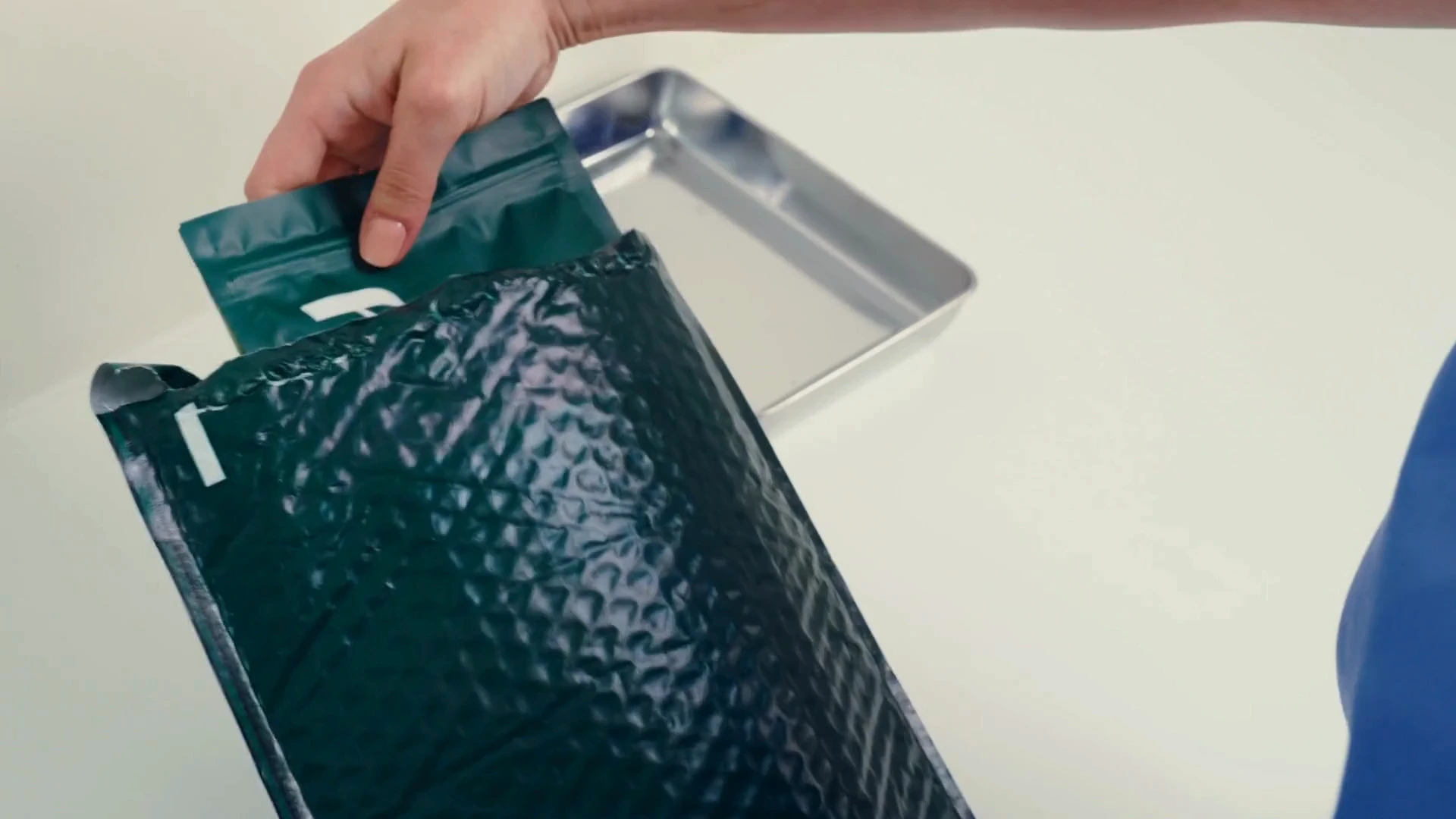 Hand placing a Dandy shipping pouch into a lab tray