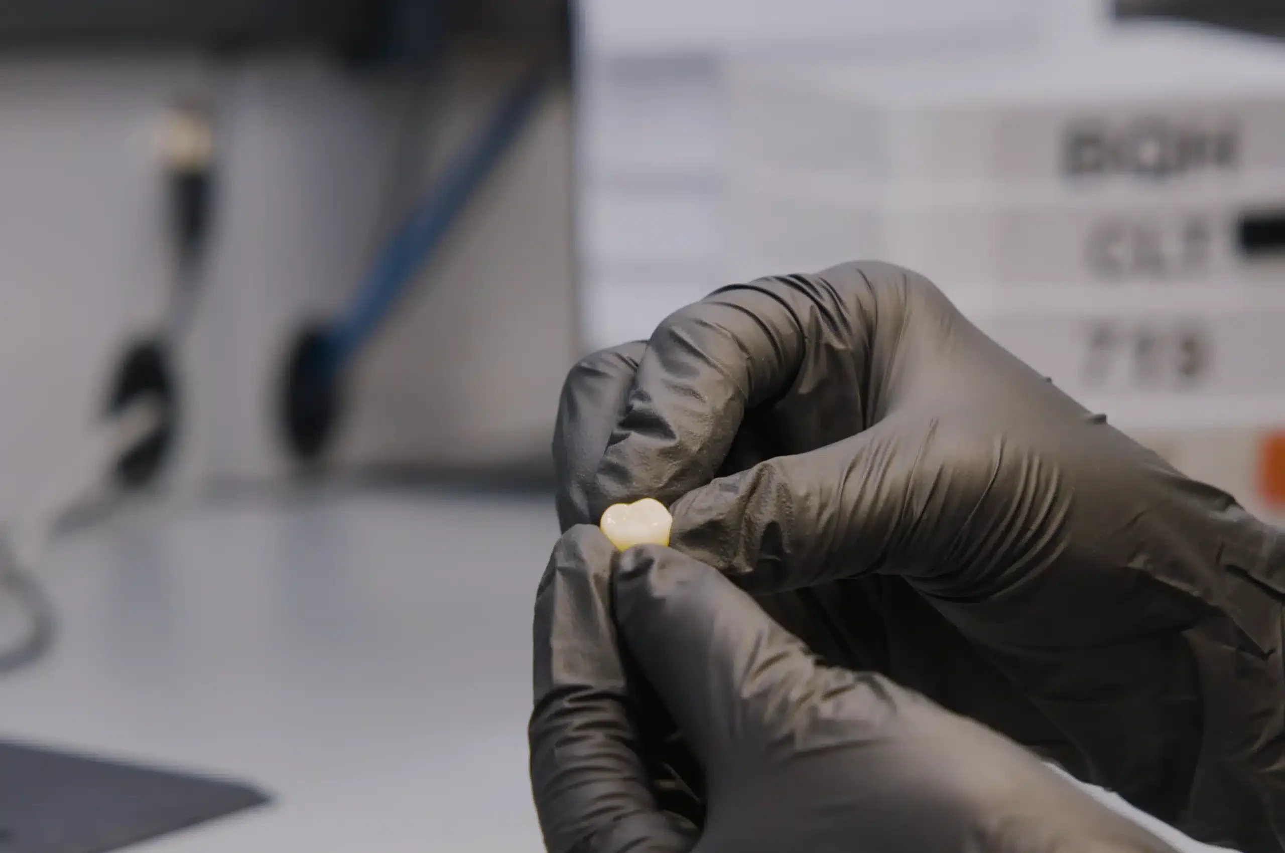 Gloved technician holding a finished crown in the Dandy lab