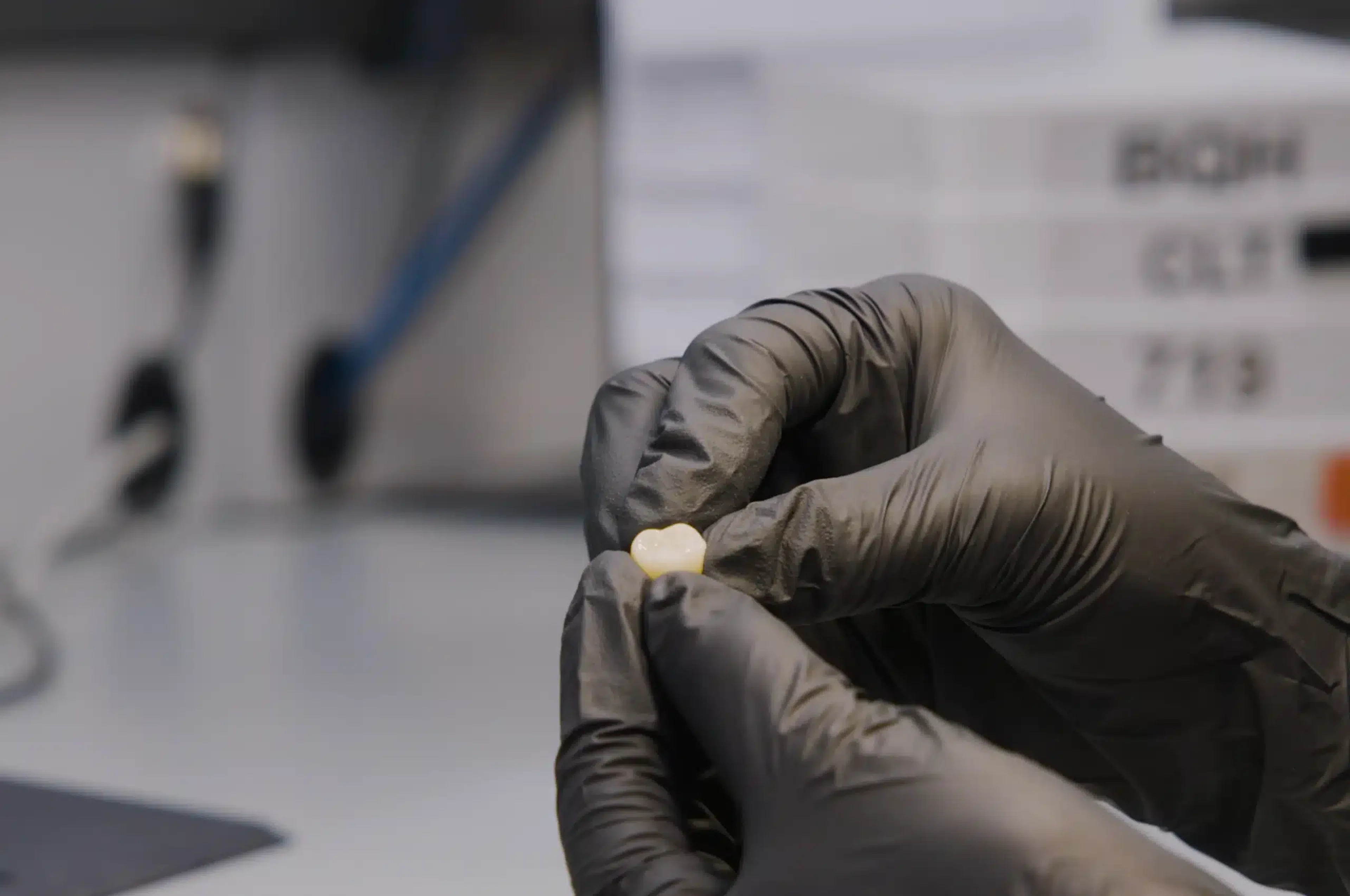 Gloved technician holding a finished crown in the Dandy lab