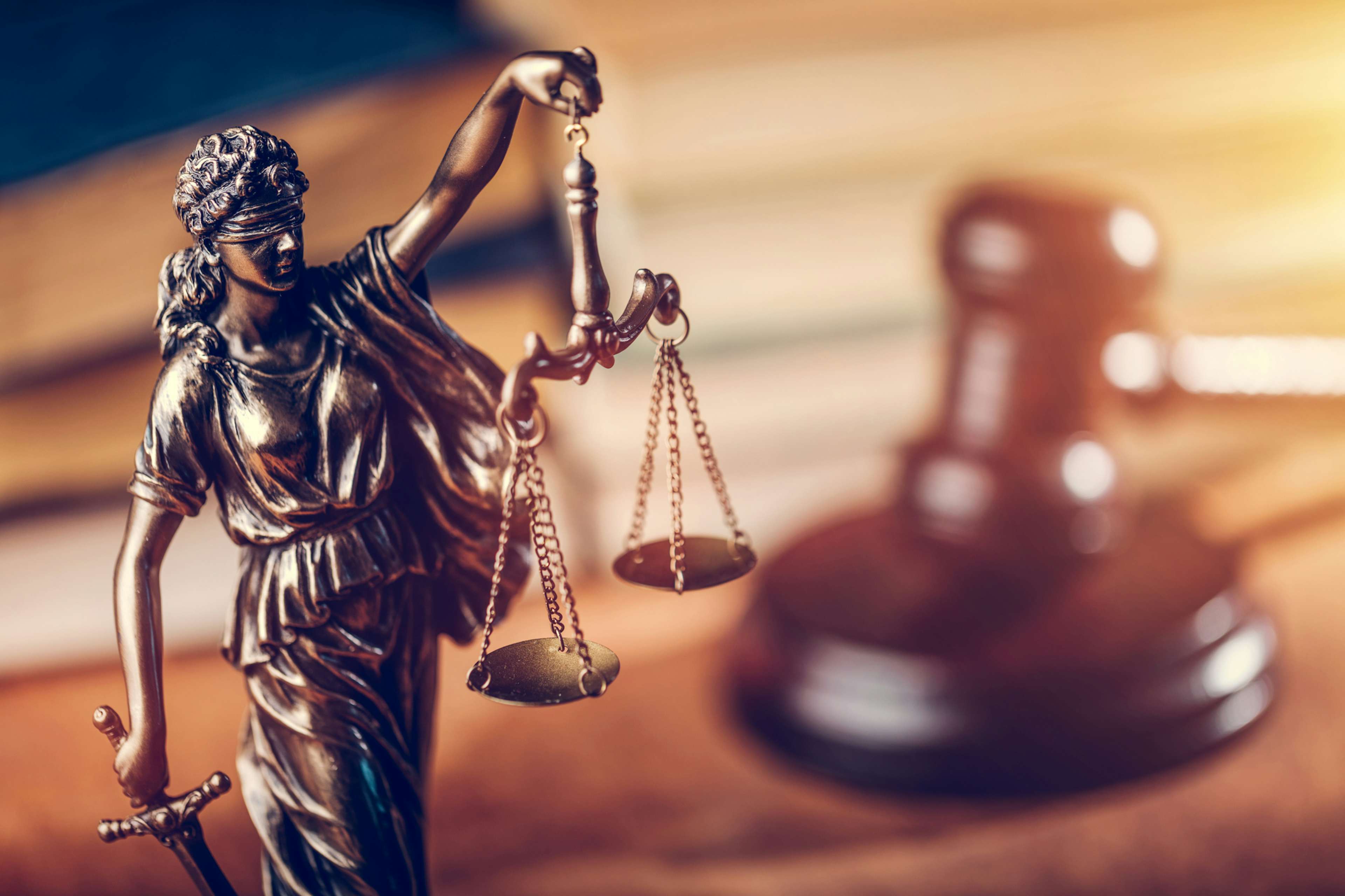 Lady justice statue with a gavel in the background