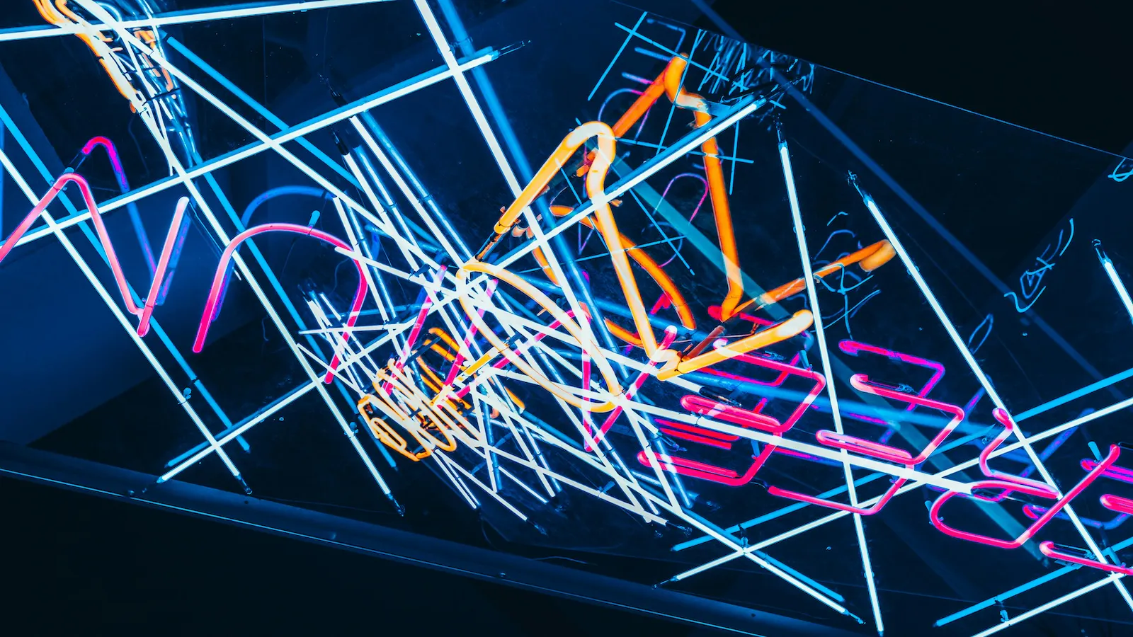 Neon lights forming abstract geometrical shapes and letters.
