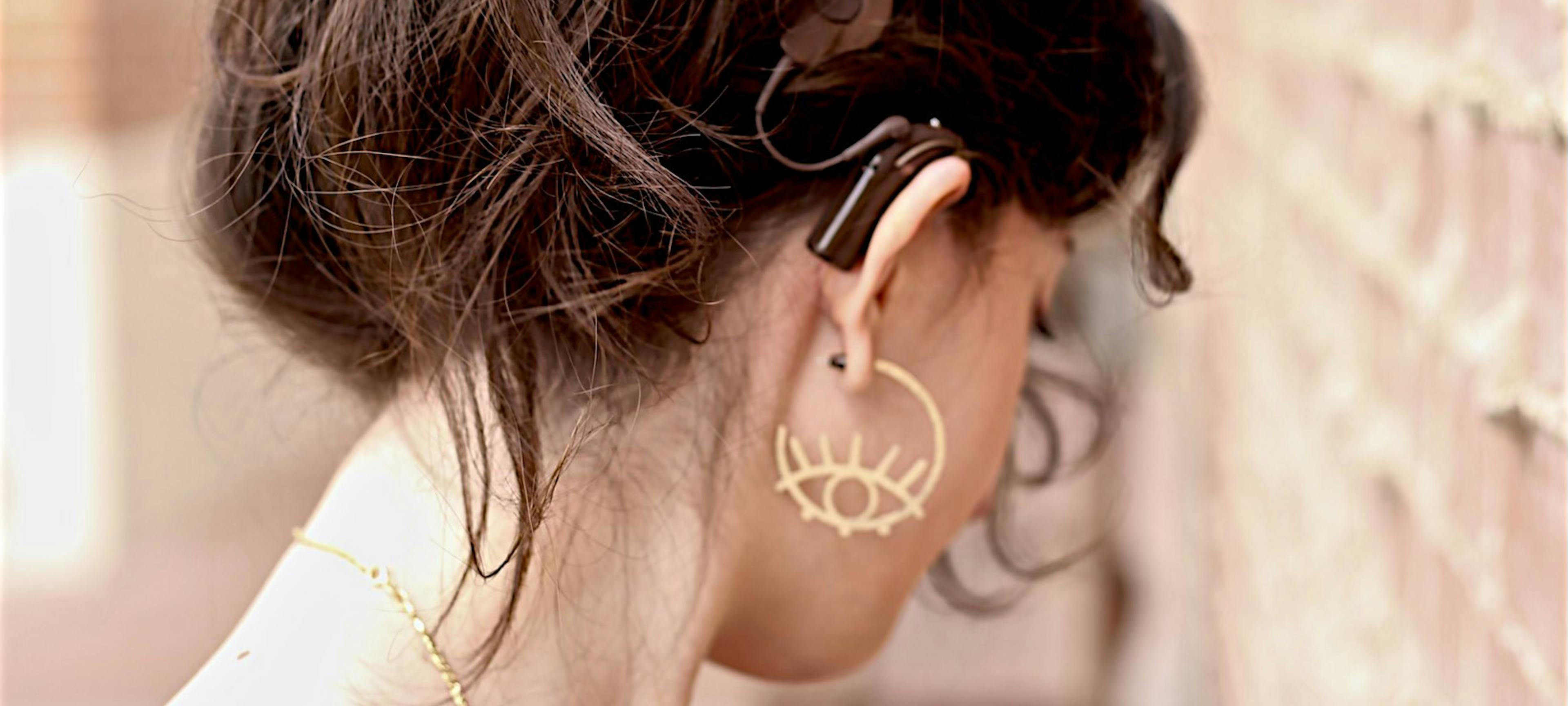 Picture of Farah's head viewed from behind with her hair in a bun, revealing her cochlear implant